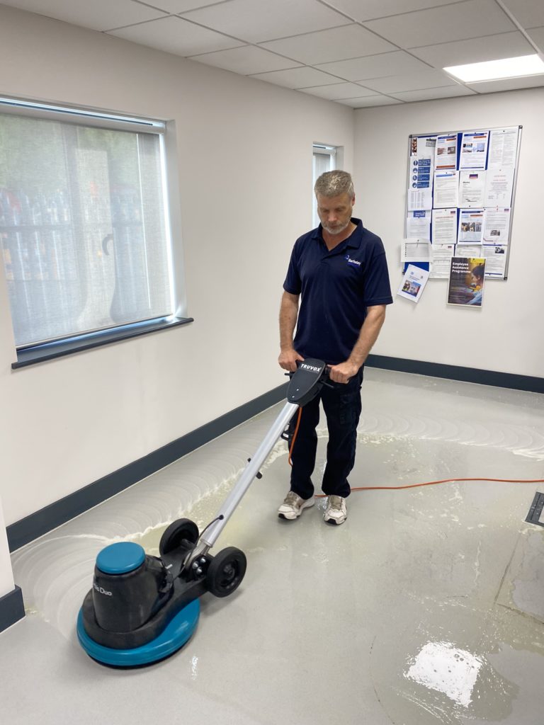 Man floor buffing and scrubbing in commercial space
